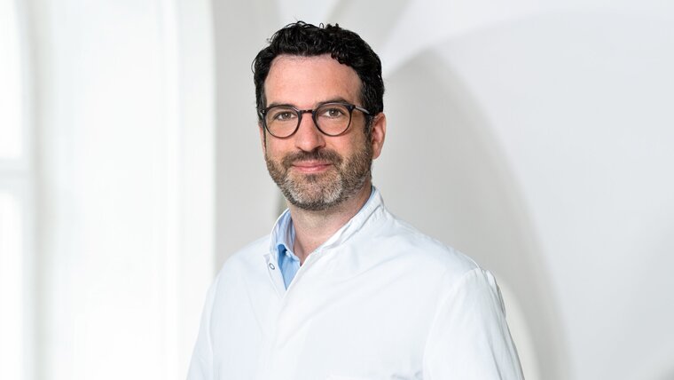  A man in a white lab coat smiling warmly at the camera.
