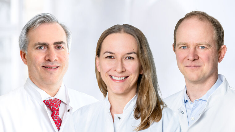  A woman and two men smile at the camera.