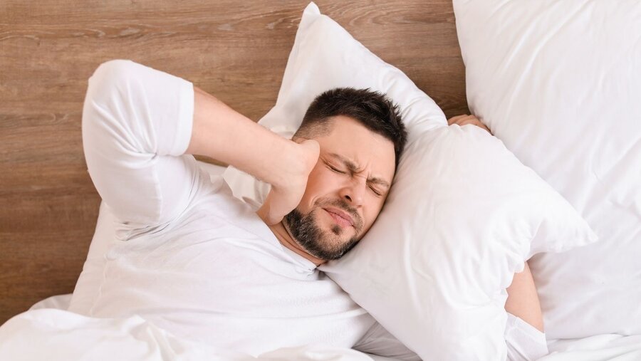 A man who lays his head on the pillow and suffers from loud noise.