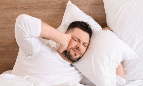 A man who lays his head on the pillow and suffers from loud noise.