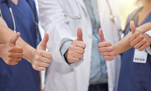 A group of doctors smiling and giving thumbs up, conveying a positive and supportive atmosphere in a healthcare setting.  