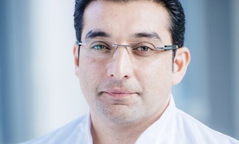  A man (PD Dr Abdul Shokor Parwan) with glasses and a white lab coat stands and smiles into the camera.