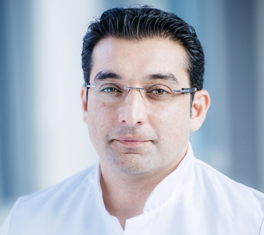  A man (PD Dr Abdul Shokor Parwan) with glasses and a white lab coat stands and smiles into the camera.