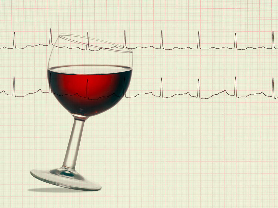 A tilted glass of red wine against the background of an electrocardiogram (ECG), which records the heart rate. 