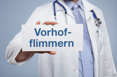 Ein Arzt hält eine Karte in der Hand, auf der „Vorhofflimmern“ steht.