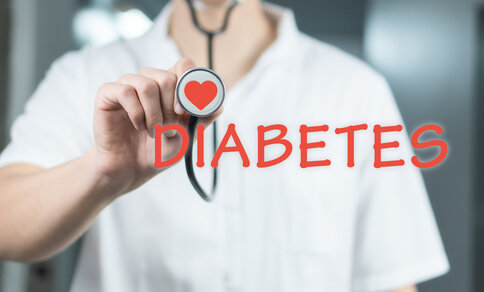A person in a white coat holds a stethoscope with a heart symbol on it. The word "DIABETES" is written in red across the image, suggesting a medical focus.
