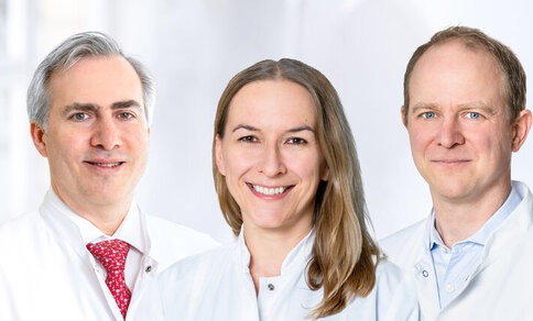  A woman and two men smile at the camera.