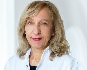 a woman in a lab coat who smiles warmly at the camera.