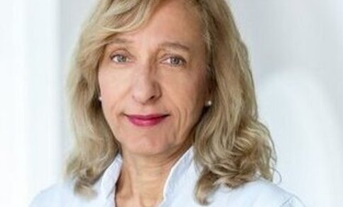 a woman in a lab coat who smiles warmly at the camera.