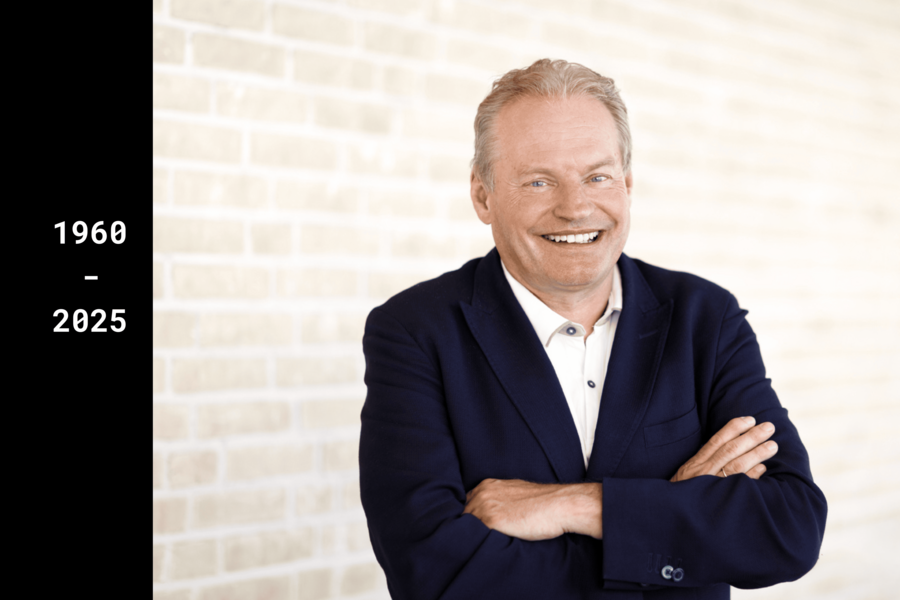  A man in a suit, identified as Professor Thomas Wieland, stands with his arms loosely crossed in front of a bright background and smiles warmly.