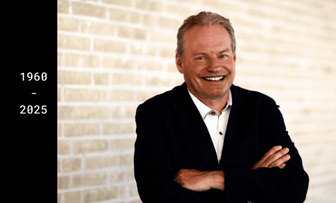  A man in a suit, identified as Professor Thomas Wieland, stands with his arms loosely crossed in front of a bright background and smiles warmly.