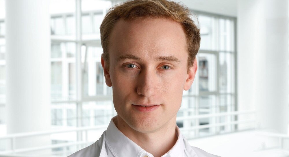 Portrait of DZHK scientist Dr Nils Krüger, first author of a study, taken at the TUM University Hospital, German Heart Centre Munich, in front of a bright, modern background.