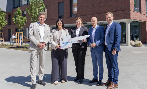 Five people are holding up a symbolic key in front of the new University Heart and Vascular Centre in Hamburg. From left to right: Prof. Dr Stefan Blankenberg, Maryam Blumenthal, Barbara Napp, Dr Peter Tschentscher and Prof. Dr Christian Gerloff.