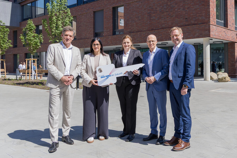 Five people are holding up a symbolic key in front of the new University Heart and Vascular Centre in Hamburg. From left to right: Prof. Dr Stefan Blankenberg, Maryam Blumenthal, Barbara Napp, Dr Peter Tschentscher and Prof. Dr Christian Gerloff.