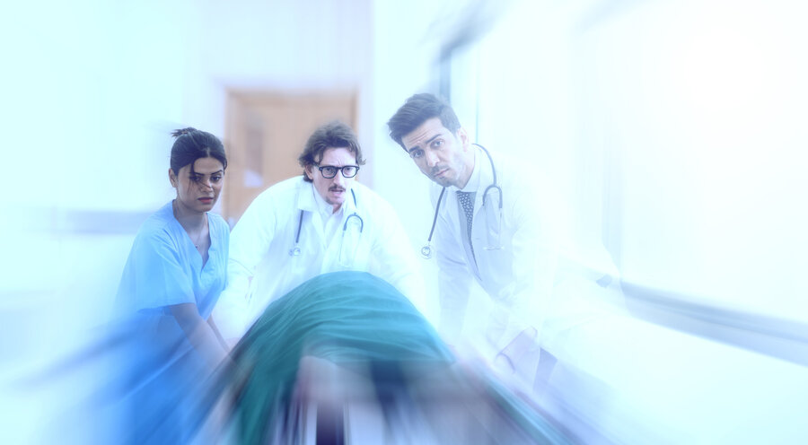 Motion-blurred view of a hospital team pushing a patient on a stretcher through a brightly lit corridor, conveying urgency and emergency medical care.