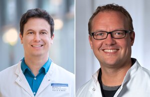  On the left, a man in a white doctor's coat (it is Prof Dr Benjamin Meder) smiles in a friendly manner. On the right, a man in a white doctor's coat (it is Dr Johannes Trebing) smiles in a friendly manner.