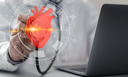 Ein Arzt oder Wissenschaftler hält ein Stethoskop an ein digitales, holografisches Bild eines Herzens. Das Bild zeigt eine EKG-Linie, die den Herzschlag symbolisiert. Im Hintergrund ist ein Laptop sichtbar, was auf den Einsatz moderner Technologien und digitaler Medizin hinweist. Um das Herz herum befinden sich Symbole, die auf medizinische Forschung und Herz-Kreislauf-Gesundheit hindeuten.