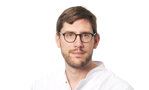 A man in a white lab coat, identified as Prof. Konstantin Stark, looks into the camera.