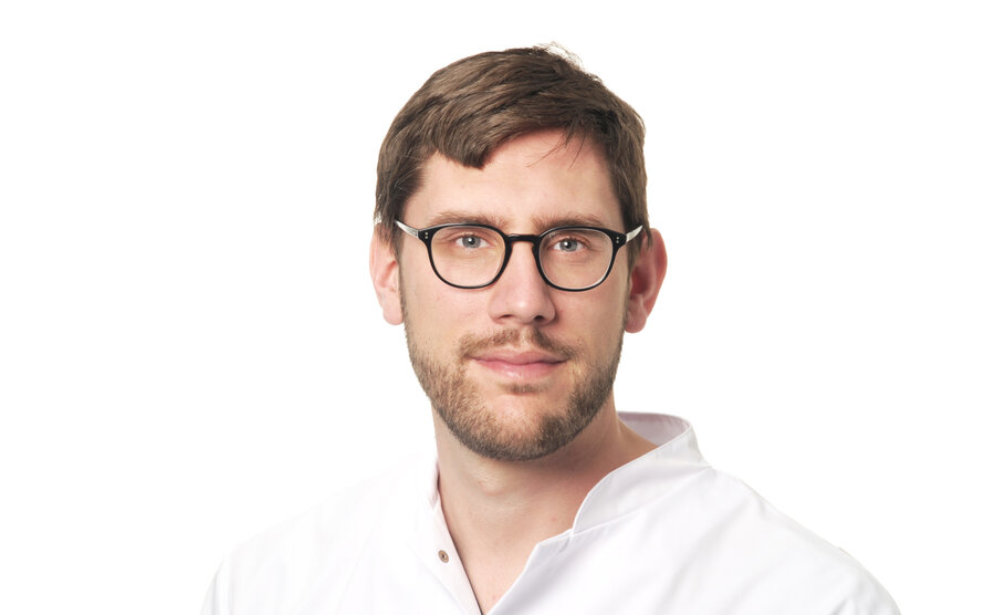 A man in a white lab coat, identified as Prof. Konstantin Stark, looks into the camera.